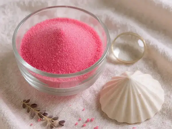 Arena fina rosa neón en un cuenco de cristal mostrando su textura y calidad para manualidades